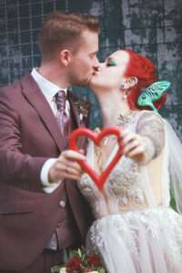 Zwei Liebende küssen sich vor einem herzförmigen Gegenstand, der ihre Gefühle symbolisiert.